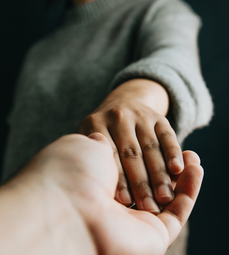 Close-up of two hands reaching out to offer trust, safety, and connection