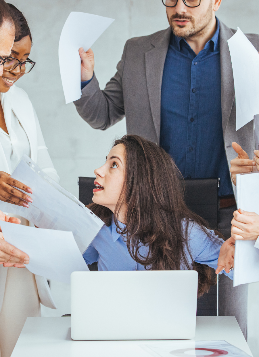 Stressed employee overwhelmed by paperwork and demands from colleagues.