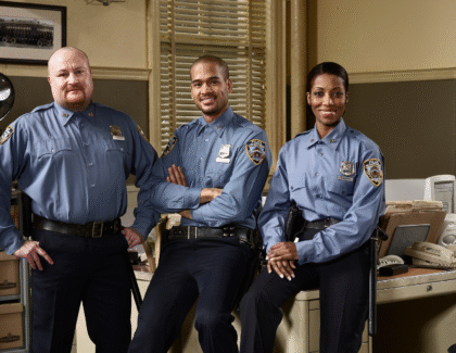 Three uniformed police officers standing confidently in a precinct office
