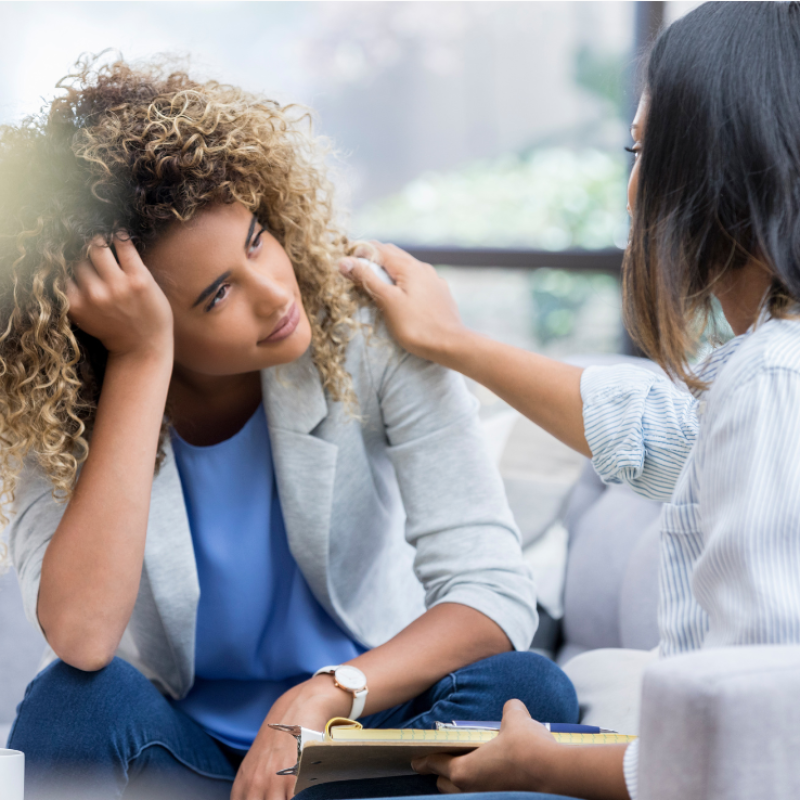 Concerned woman receiving empathetic support from a counselor in a therapeutic setting